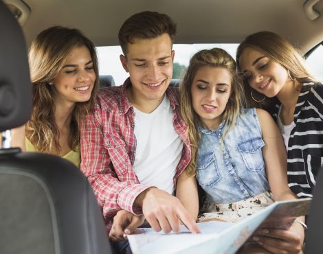 friends-sitting-back-car-s-seat-pointing-map